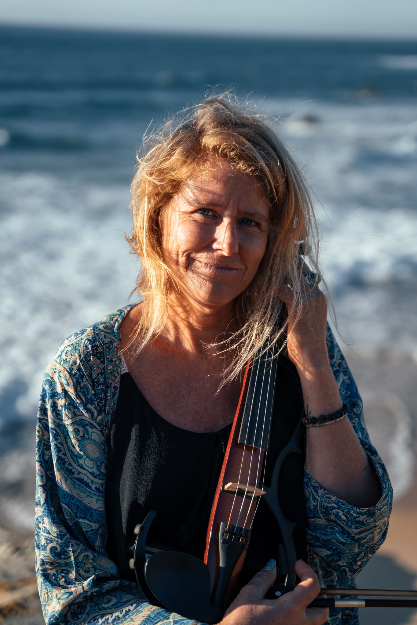 Maelle posing with her violin on the beach